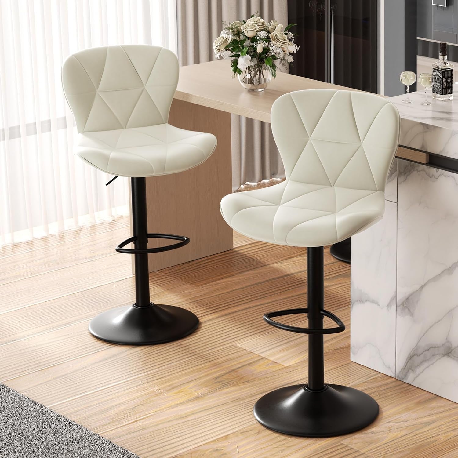 Close side view of two cream bar stools showing diamond-stitched backs and round black bases.