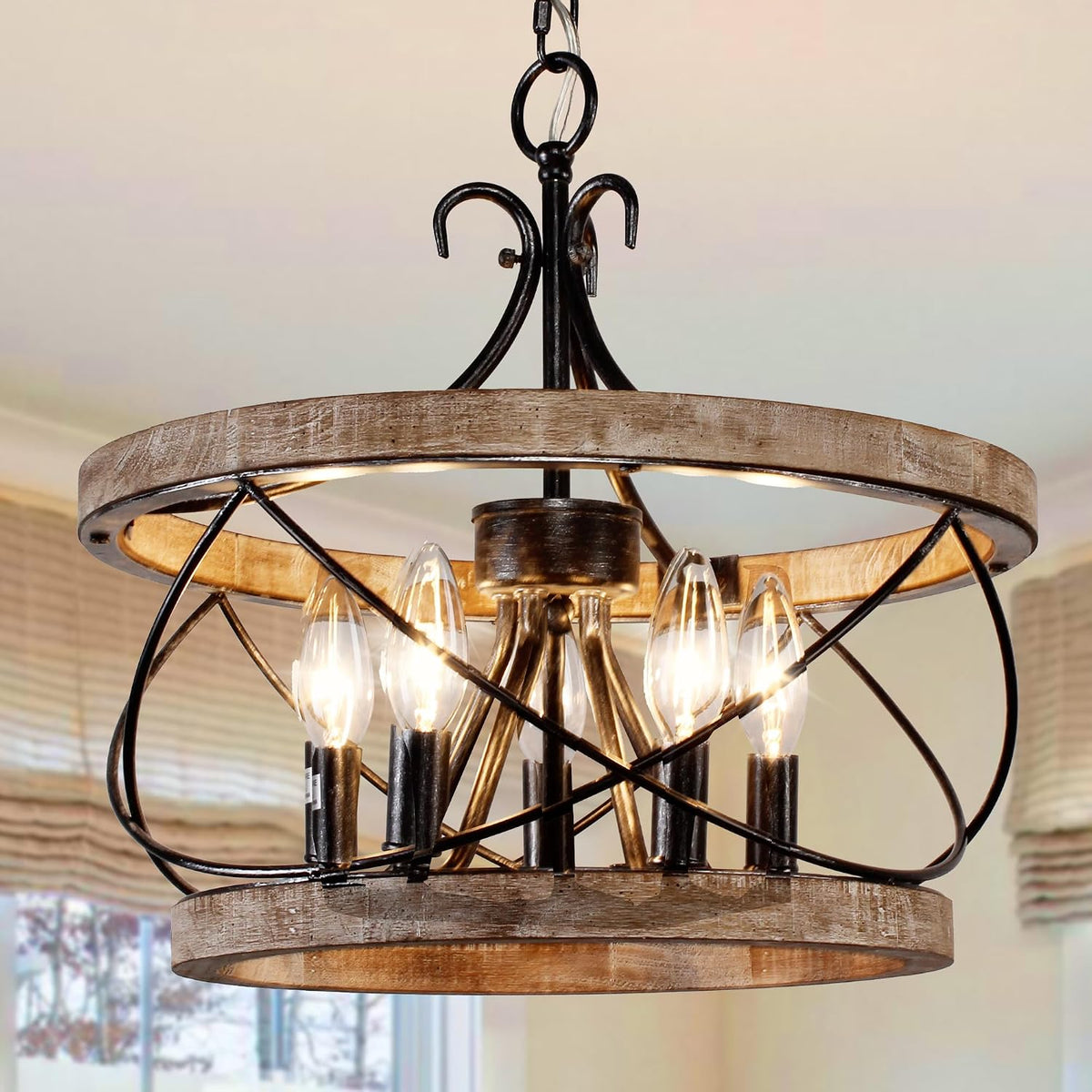 Close-up of the wood drum chandelier showing hand-painted wood ring, black iron swirls and five candle-style bulbs