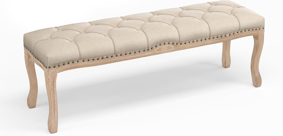 Low three-quarter view of a light beige tufted bench highlighting the carved apron and cabriole legs