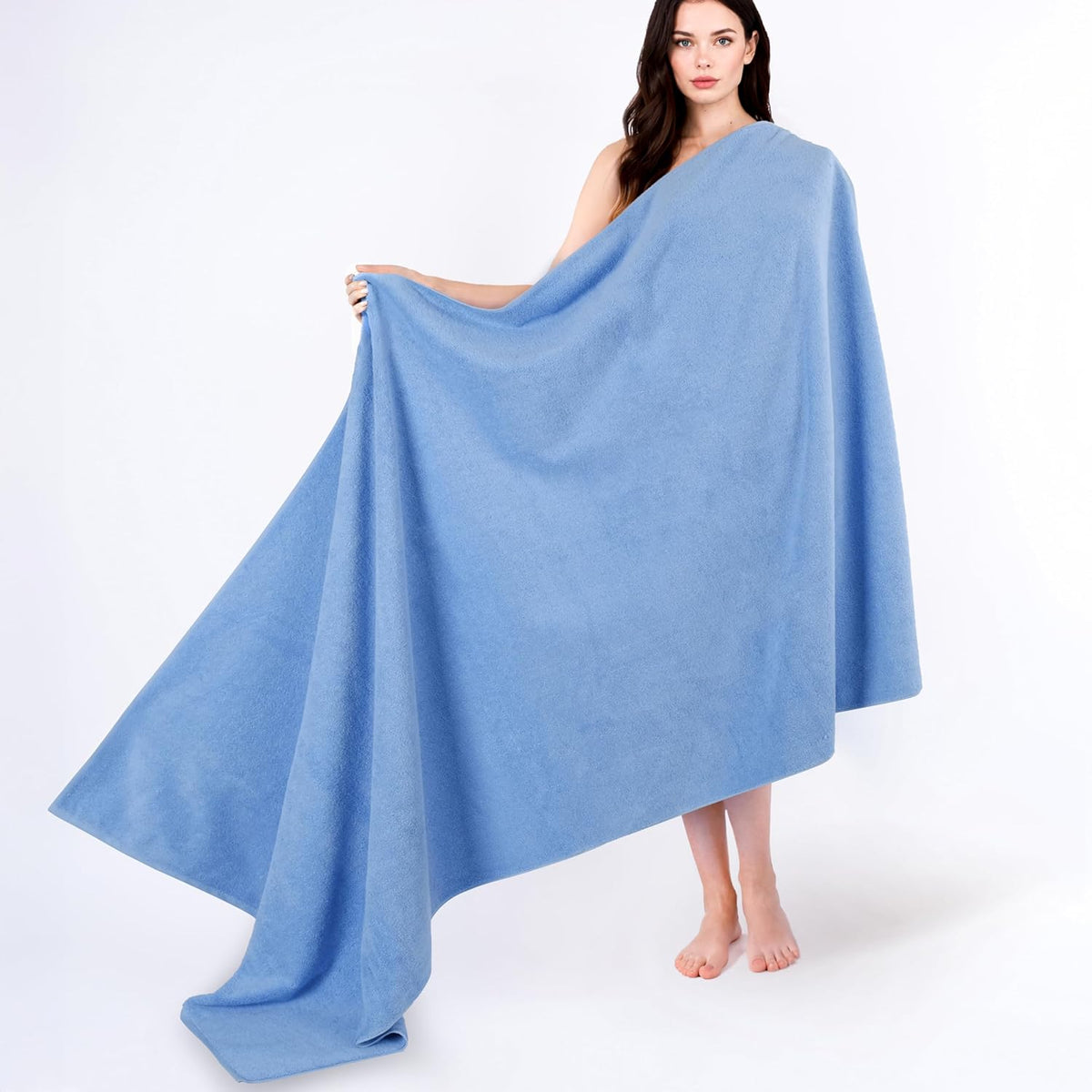 Model draped in and holding a large light blue towel spread wide