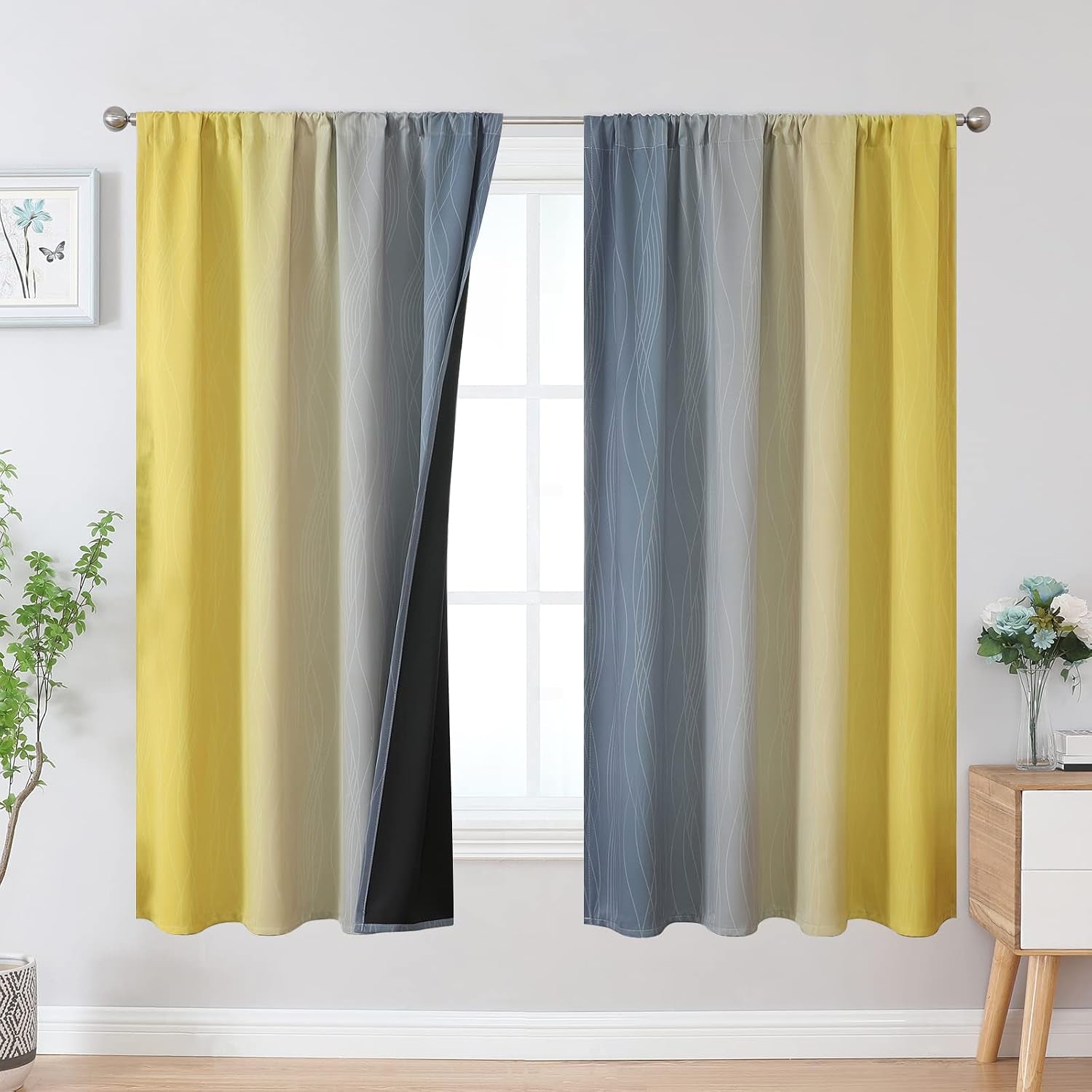 Window dressed with yellow-to-blue ombre patterned curtains, left panel pulled back to show black lining behind.