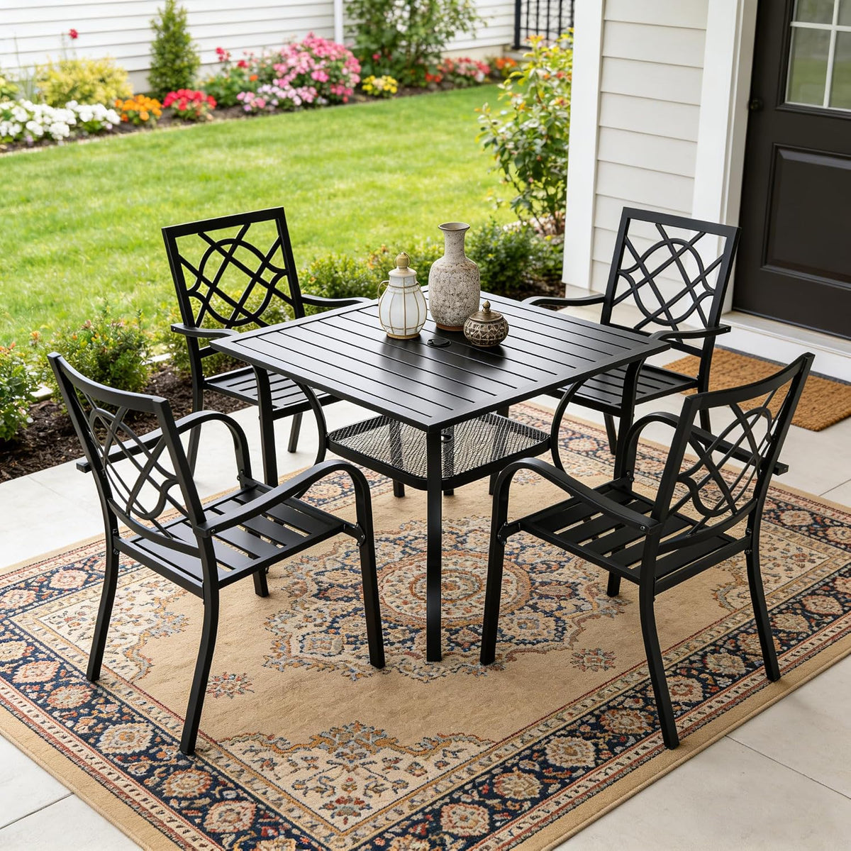 Black metal 5-piece patio dining set on a patterned outdoor rug on a porch, front view highlighting the chair back design.