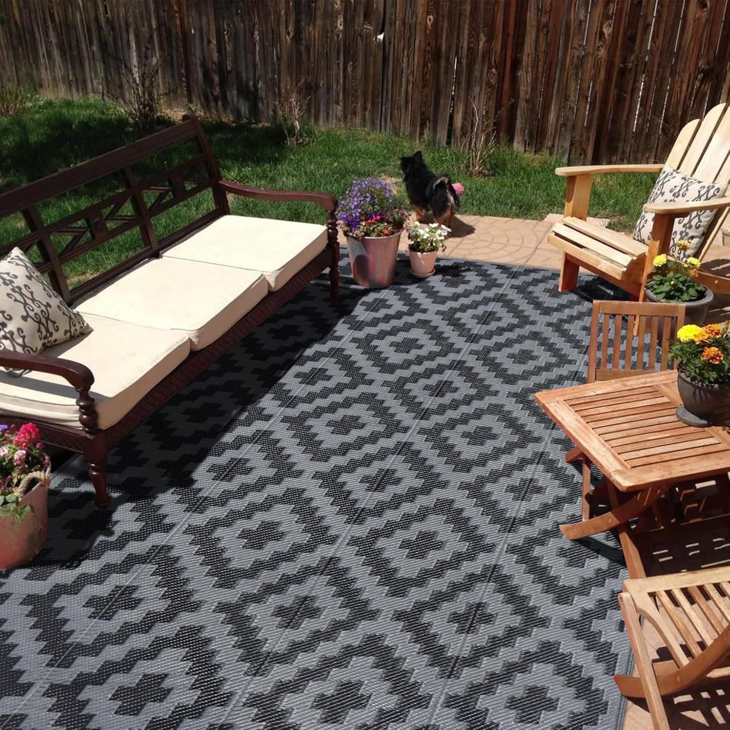 Sunny backyard patio with wooden chairs and a dark gray geometric outdoor rug.