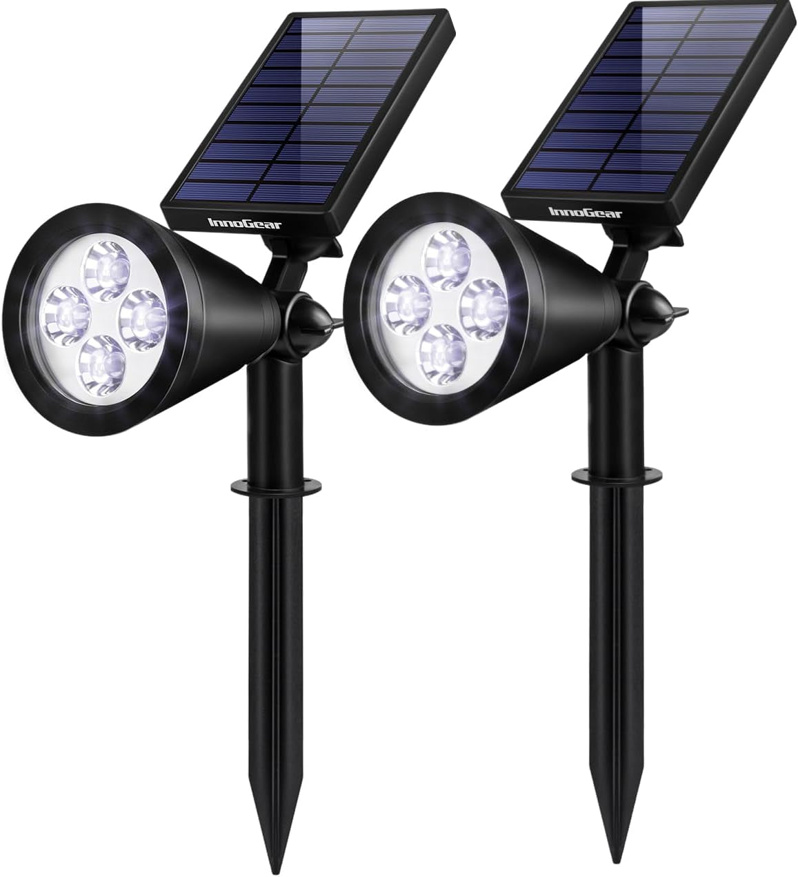 Close pair of black solar stake spotlights showing angled solar panels and four illuminated LED lenses.