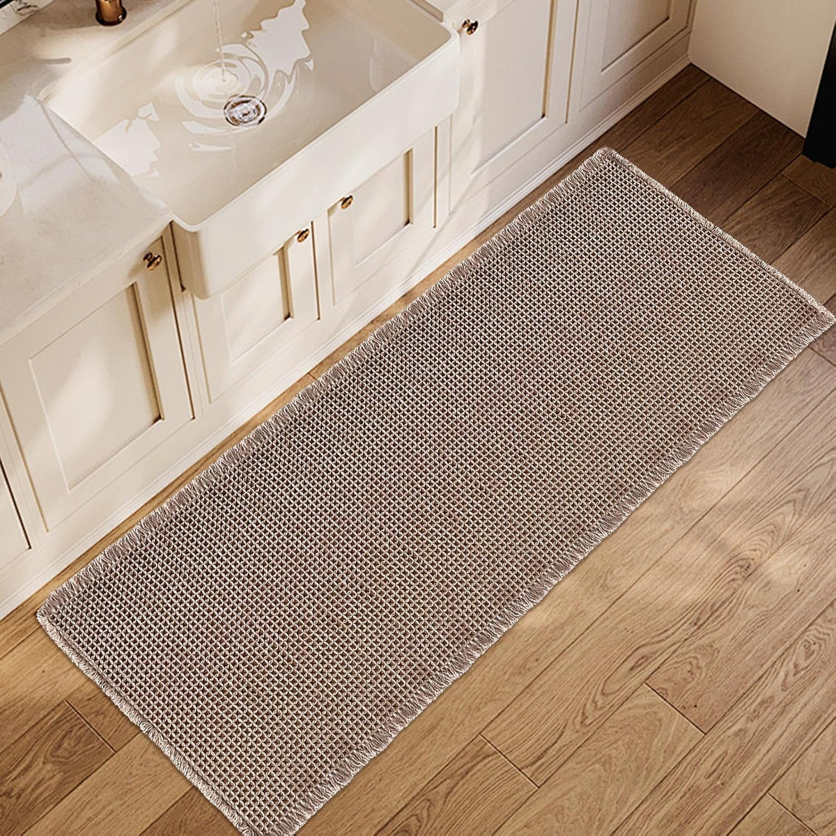 Light brown waffle bath runner placed along a sink cabinet on wood floor