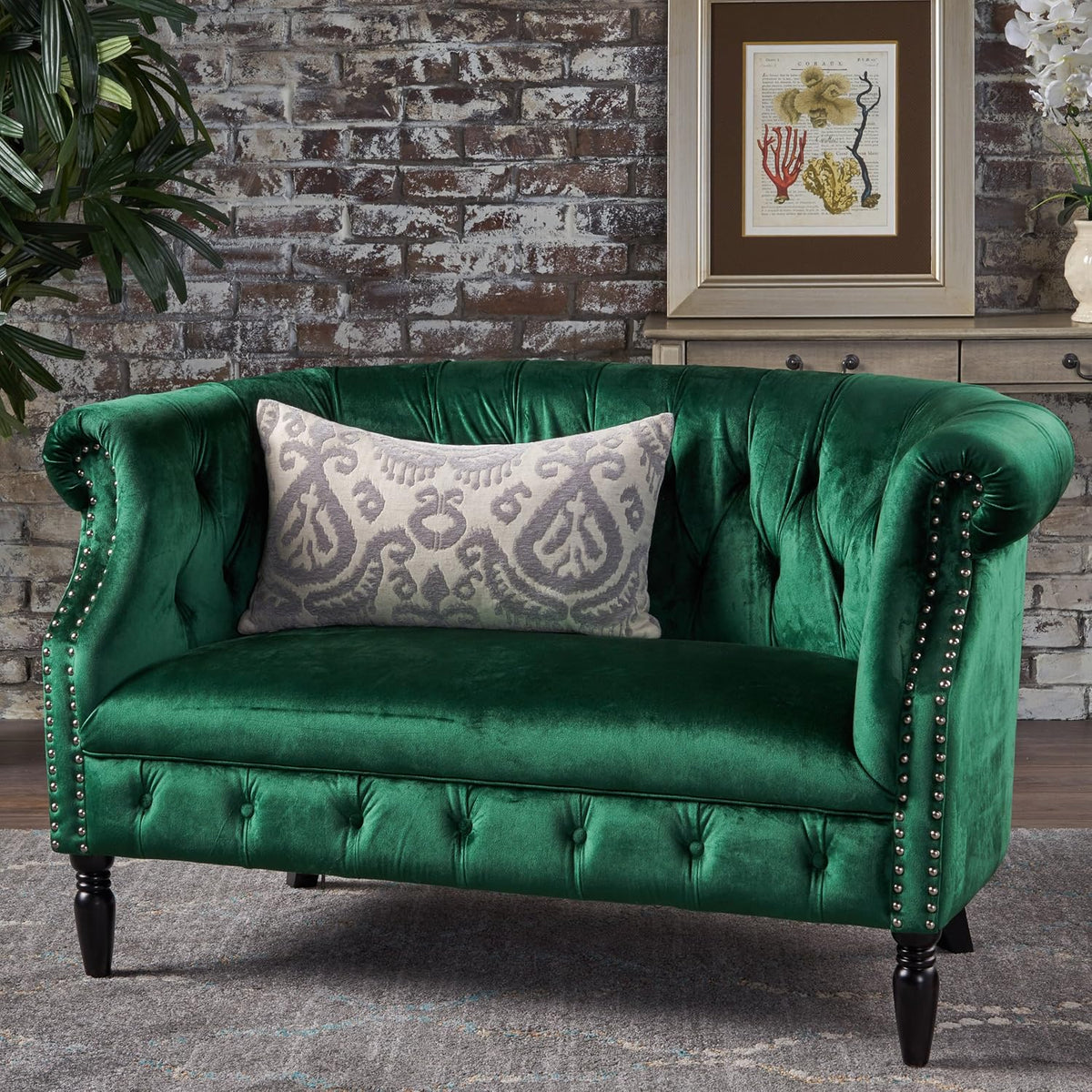 Emerald velvet tufted Chesterfield loveseat front view with patterned lumbar pillow in a living room setting