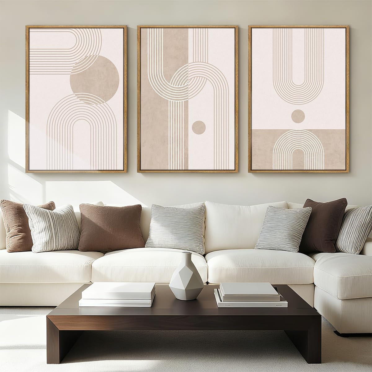 Living room scene with cream sectional sofa and three framed minimalist beige abstract prints above a dark wood coffee table.