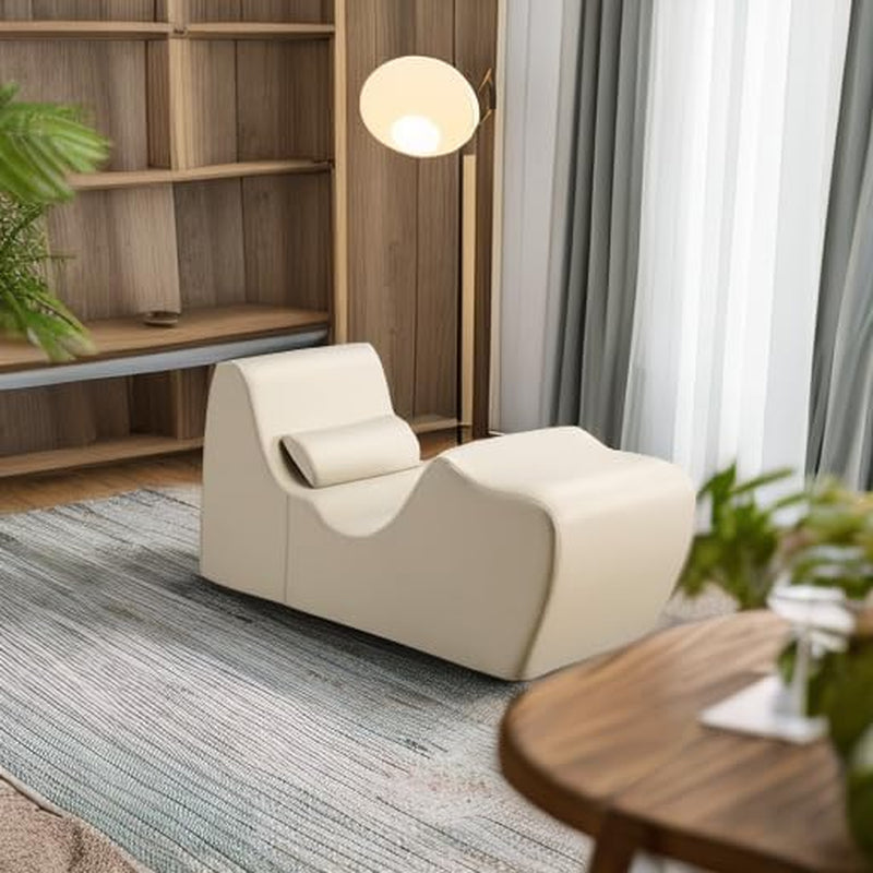 Oatmeal chaise lounger placed in a living room with floor lamp and shelving, angled view on a rug