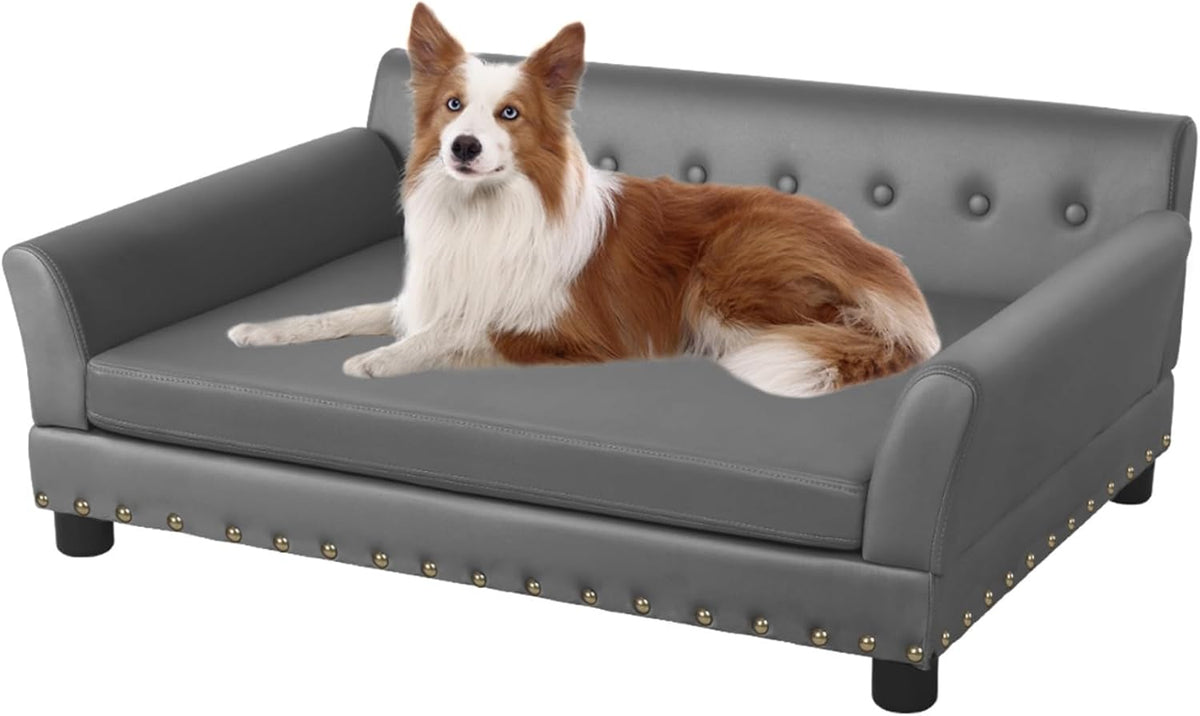 Gray elevated leather-look dog sofa with buttoned back, nailhead trim and a brown-and-white dog lying on the cushion