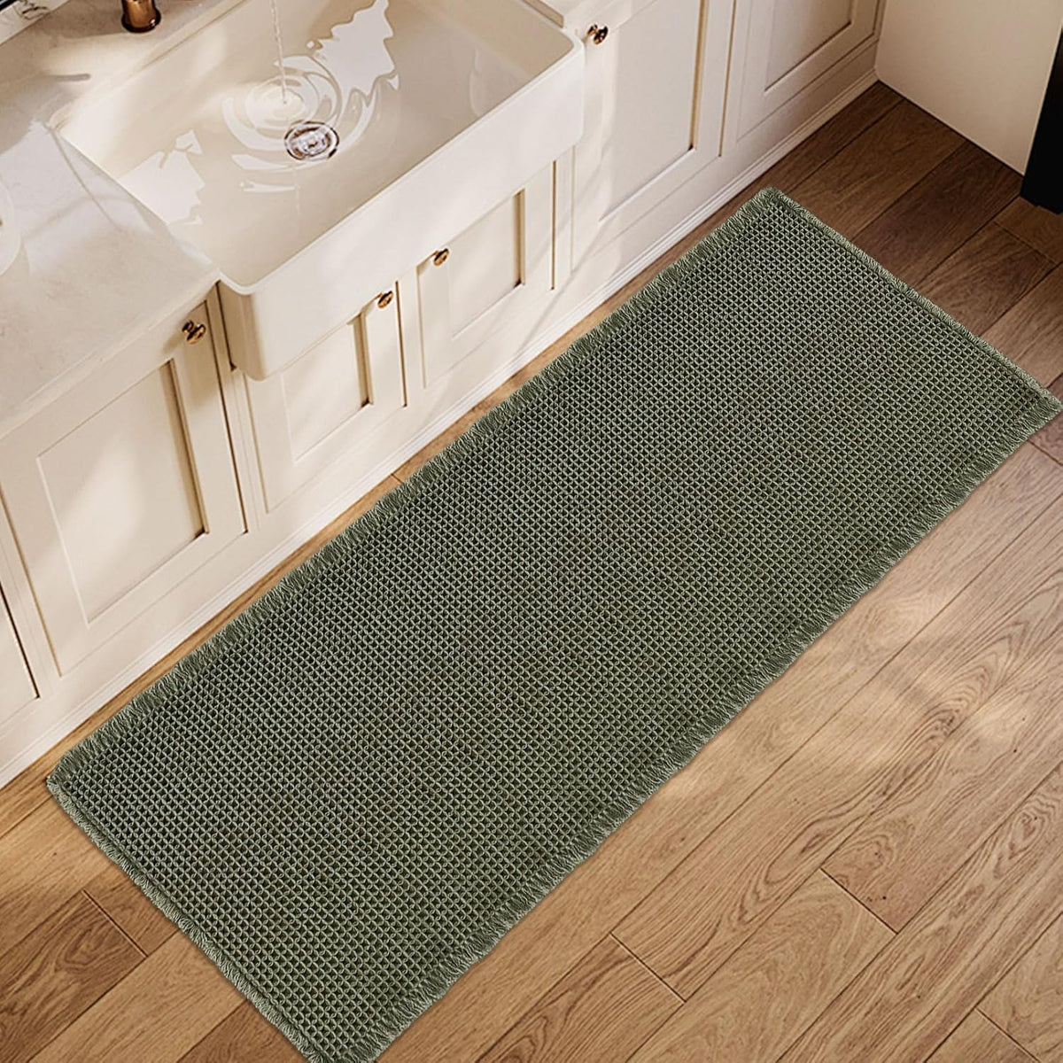 Top-down view of an olive-green waffle runner placed along a vanity on wood flooring.