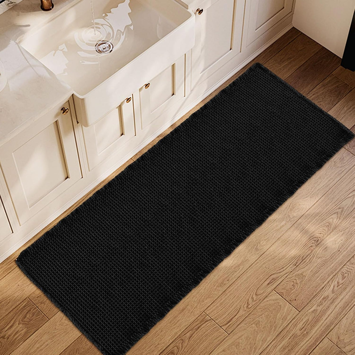 Overhead view of a black waffle runner laid along a vanity on wood flooring.