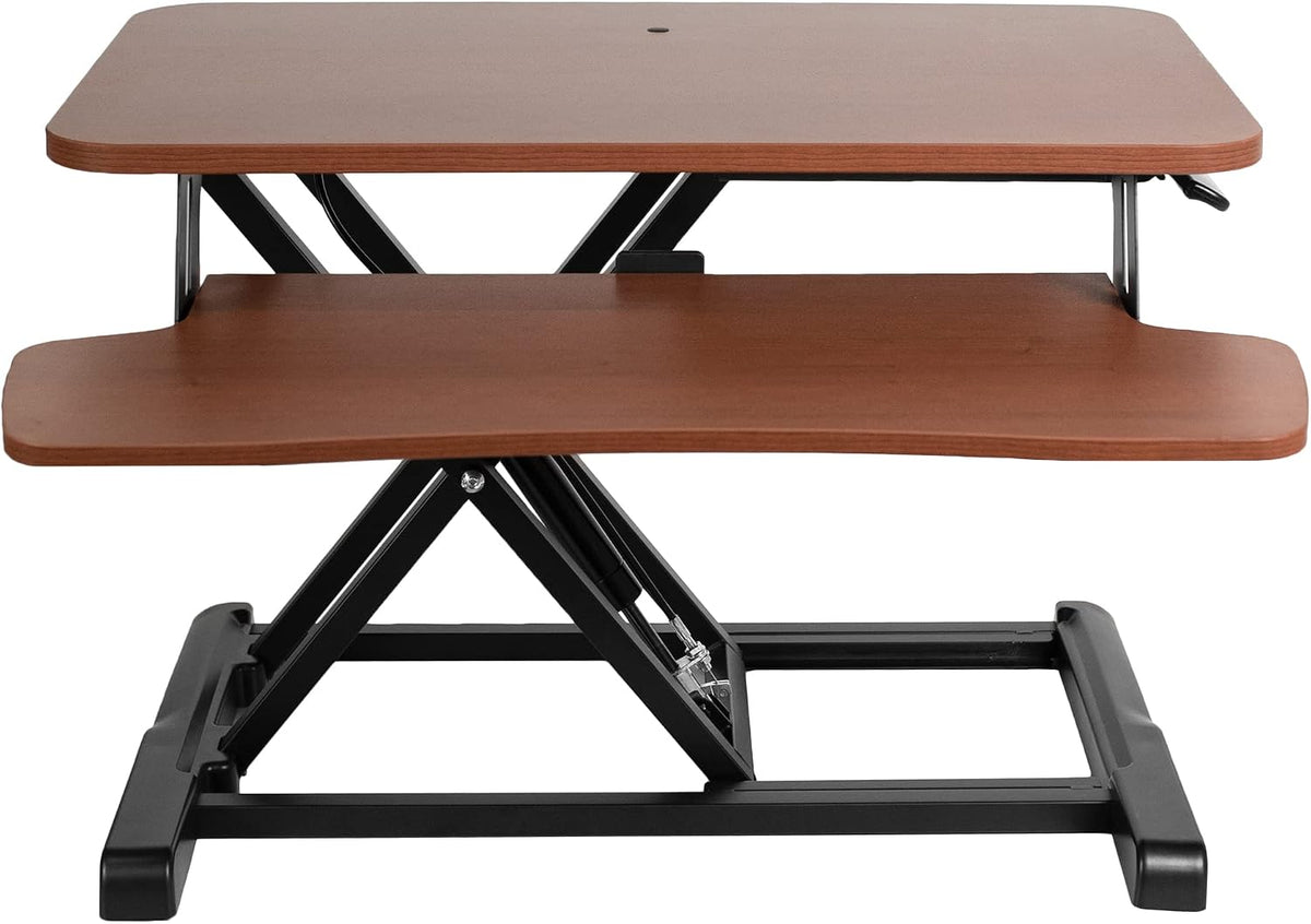 Front view of a medium brown wood standing desk converter with black metal base and keyboard shelf.