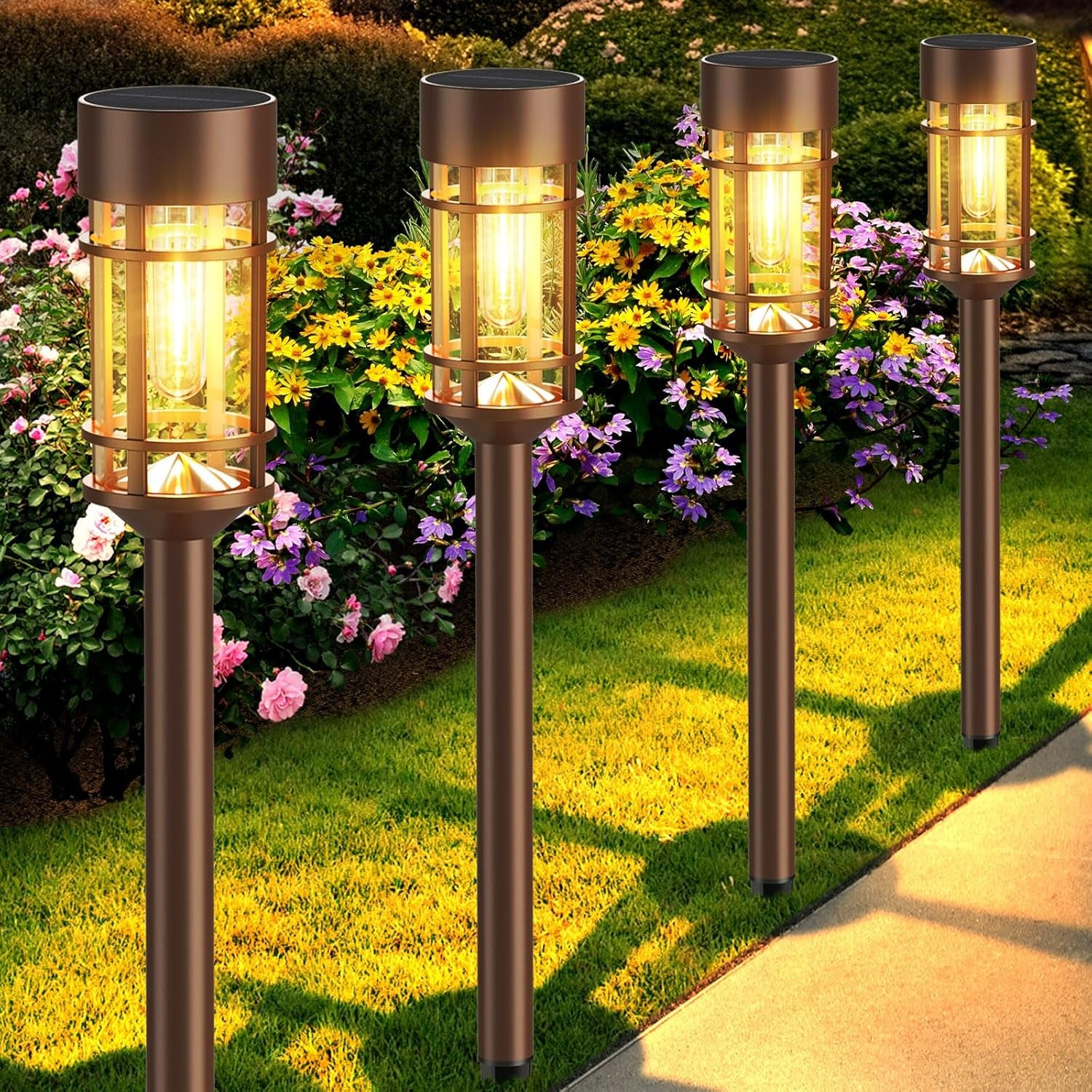 Five warm-lit solar stake lights in a line beside a flowerbed and sidewalk.