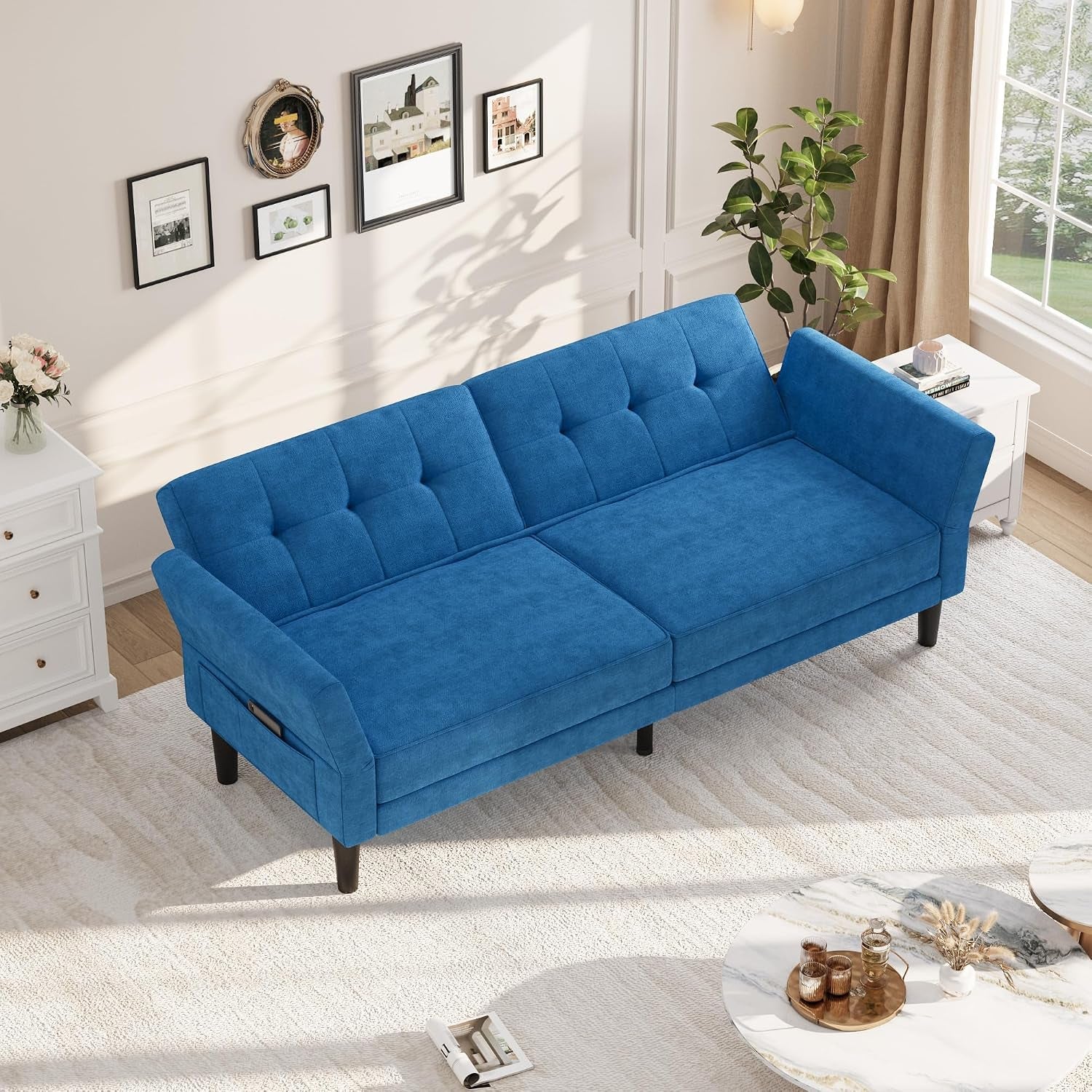 Top-down view of blue futon in sofa position with tufted back and one arm partially lowered