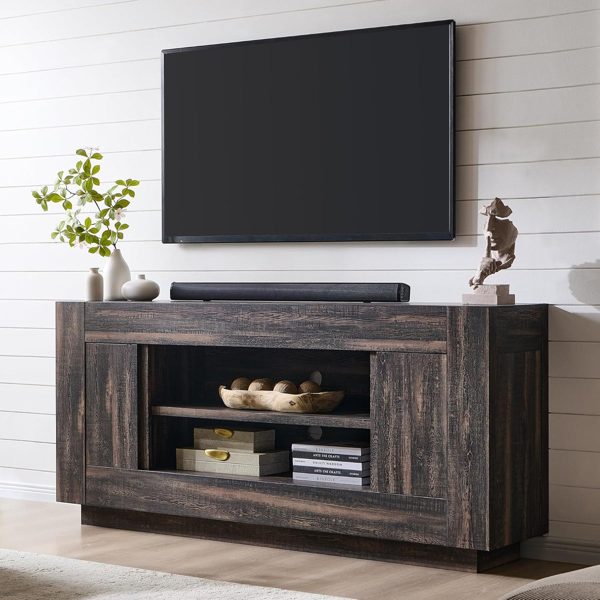 Dark wood TV console with central open shelves beneath a wall-mounted TV and decorative vases