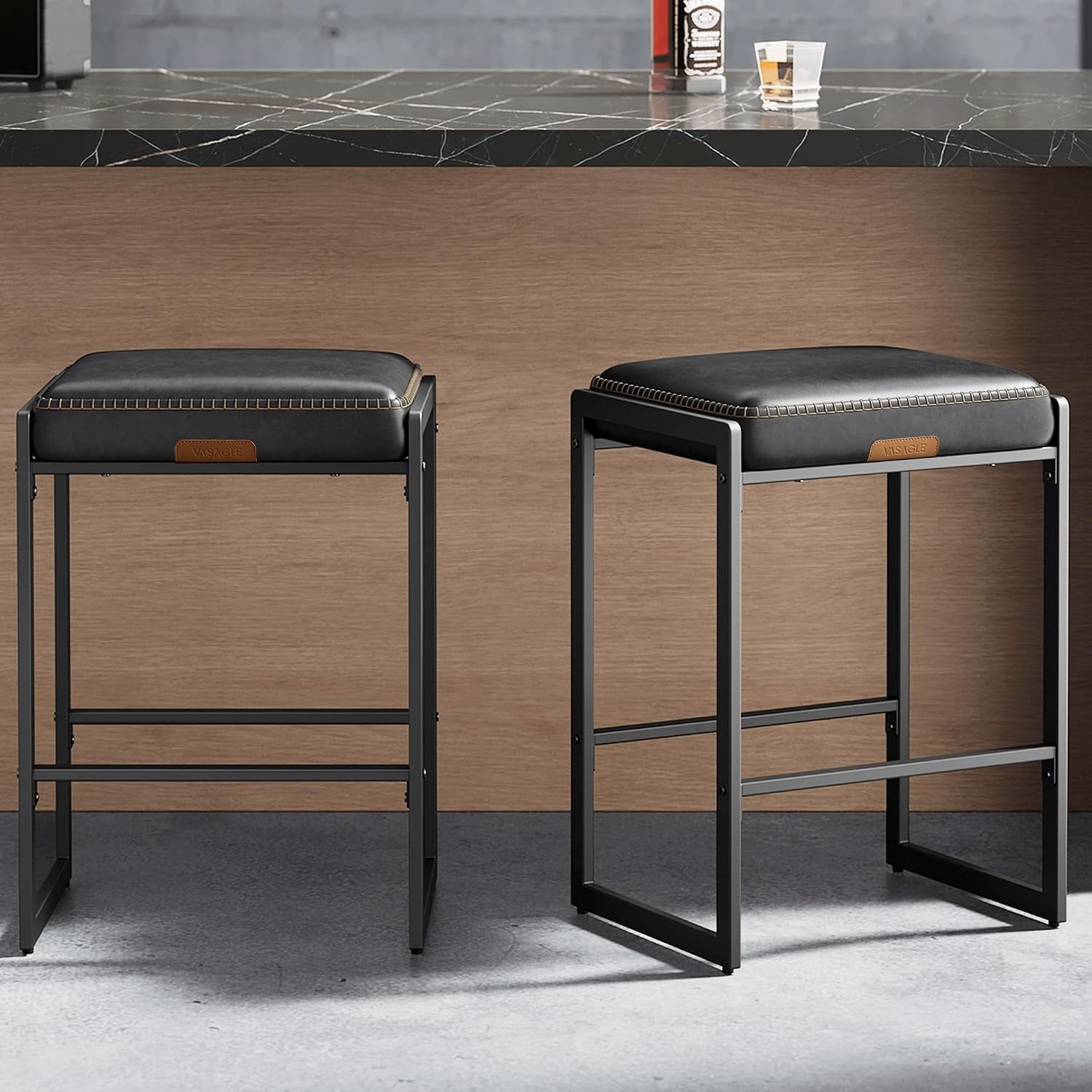 Two counter-height stools with black PU cushions and matte black rectangular metal frames side by side under a counter.