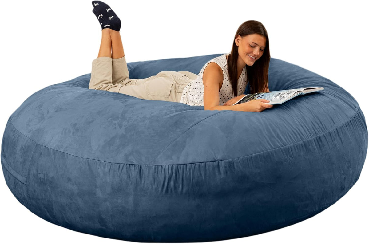Large round blue-gray bean bag with a woman lying on it reading a magazine