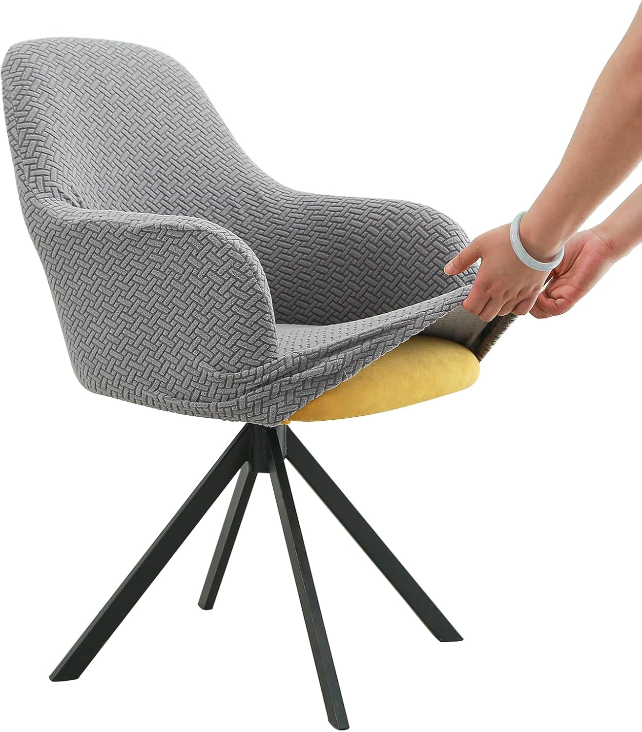 Side view of a swivel armchair with a textured gray stretch cover being pulled over the seat by two hands wearing a bracelet.