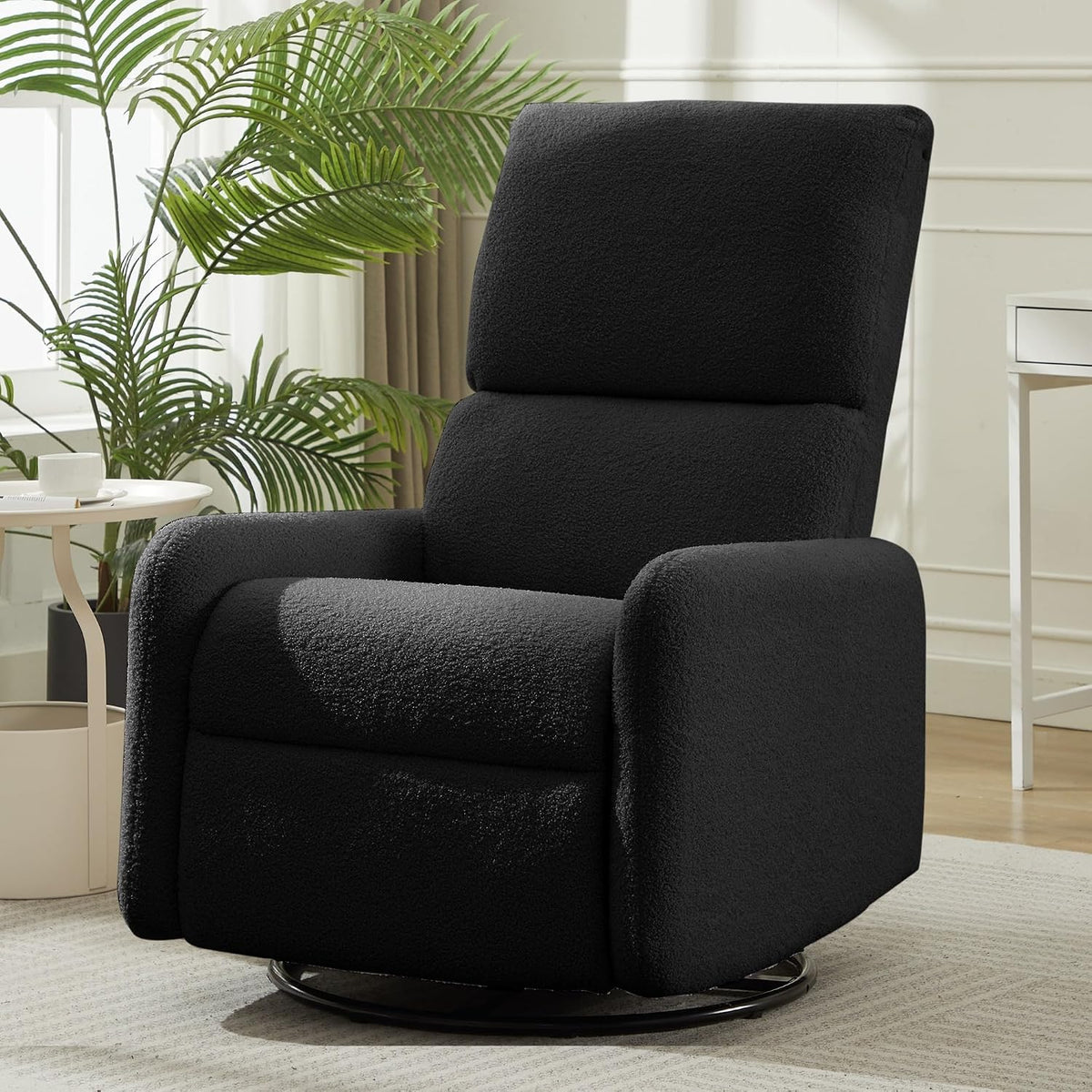 Black sherpa swivel rocking chair with rounded arms on a round metal base in a sunlit room with plant and side table.