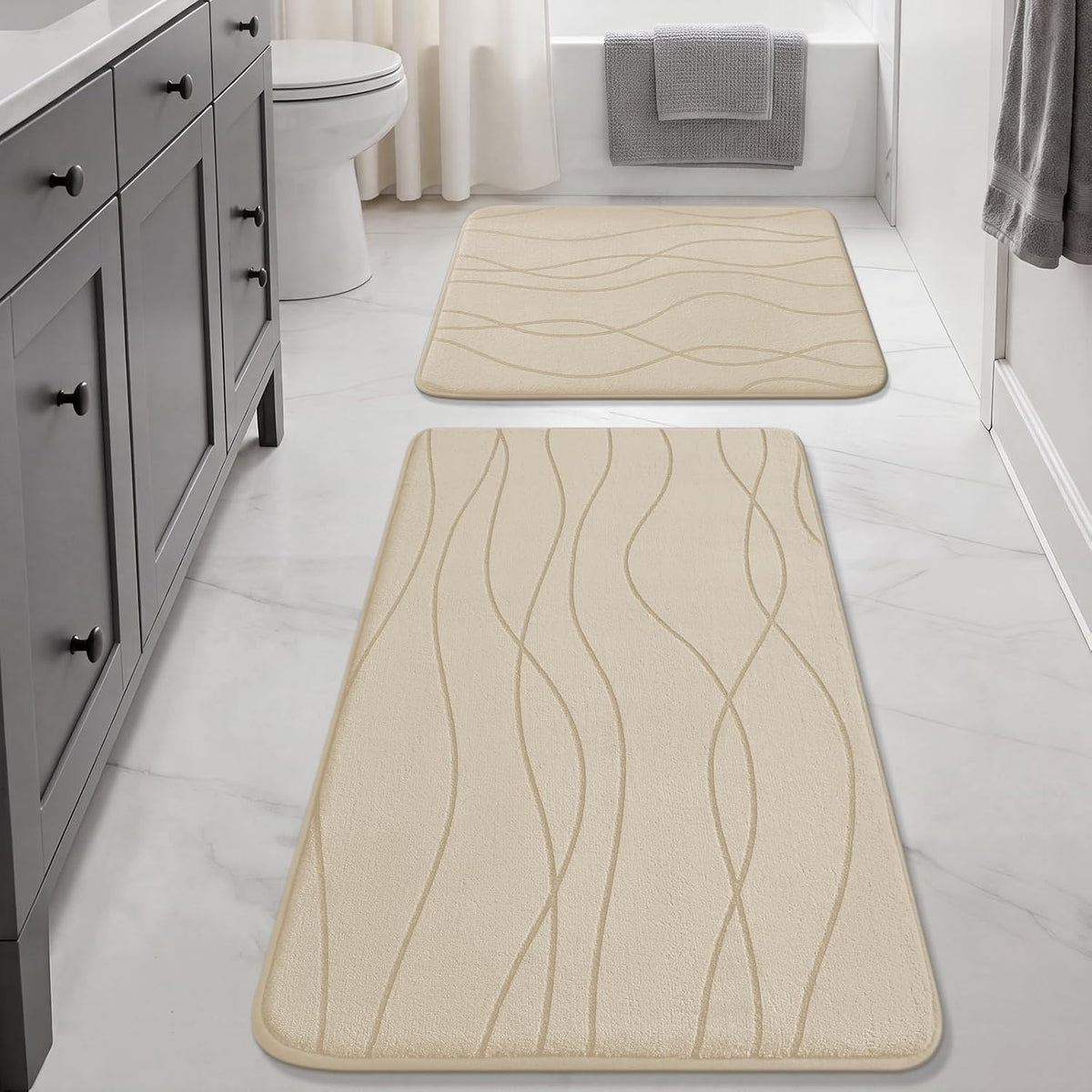 Long beige runner and smaller matching rug on a white-tiled bathroom floor by a gray vanity and tub.
