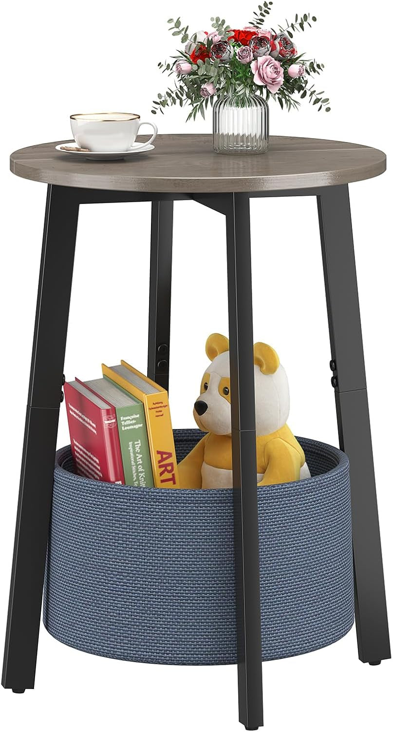 Round table with gray wood top and black legs, lower blue cloth basket holding books and a stuffed bear