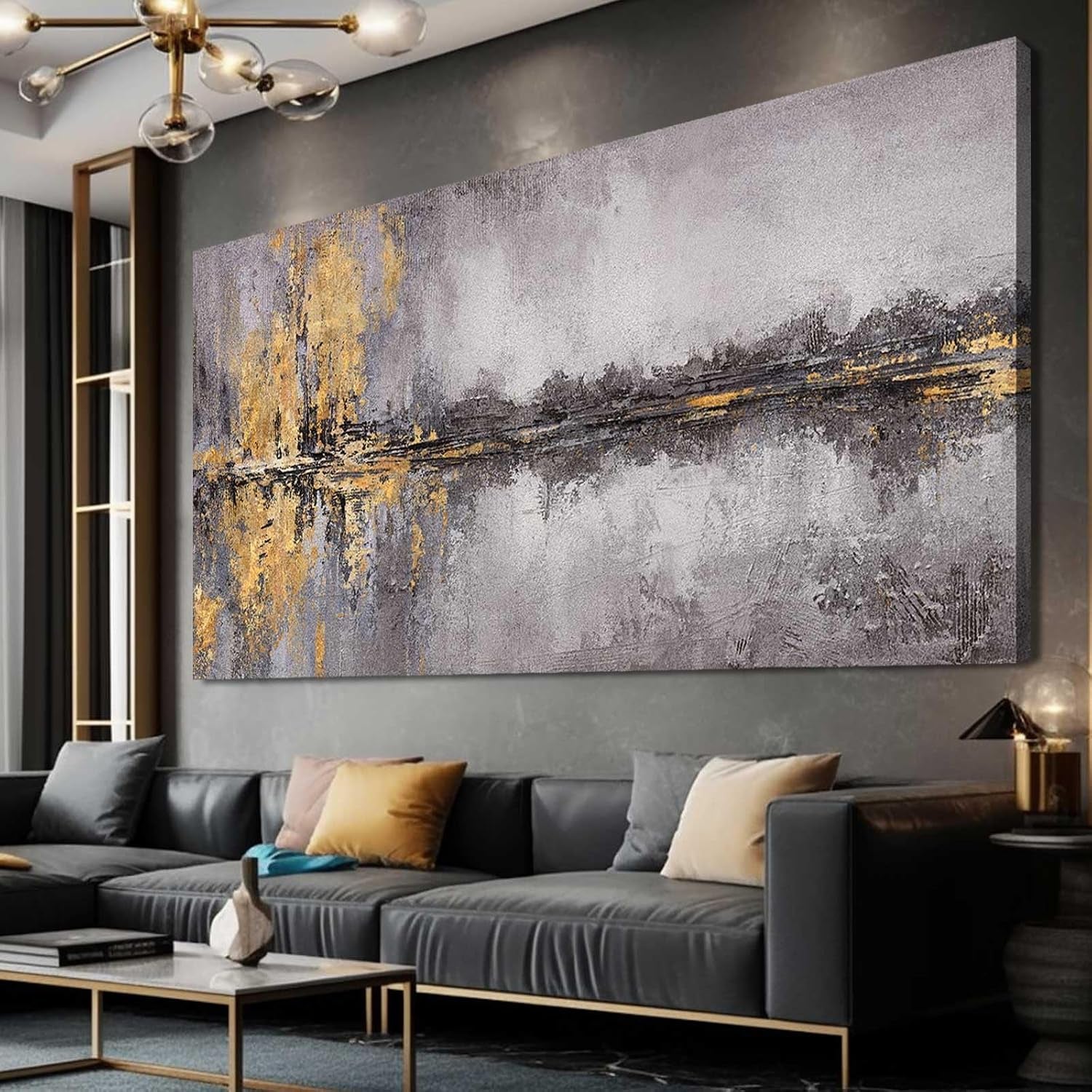 Angled view of a large textured abstract canvas with gold and gray streaks above a dark gray sectional sofa in a modern