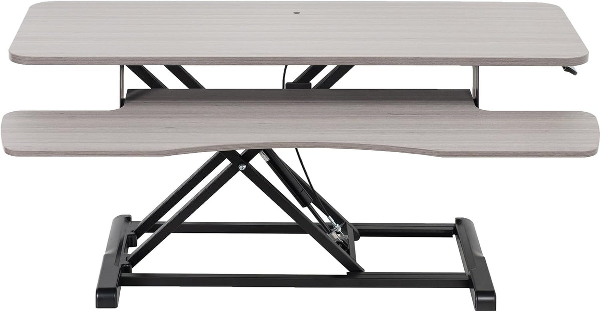 Front-facing view of the desk converter in a light wood finish showing the top surface, keyboard tray and scissor lift.