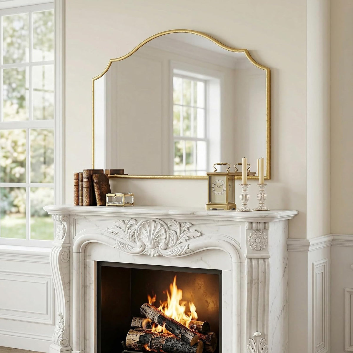 Front view of gold scalloped arched mirror over a white mantel with a clock, books, and candles