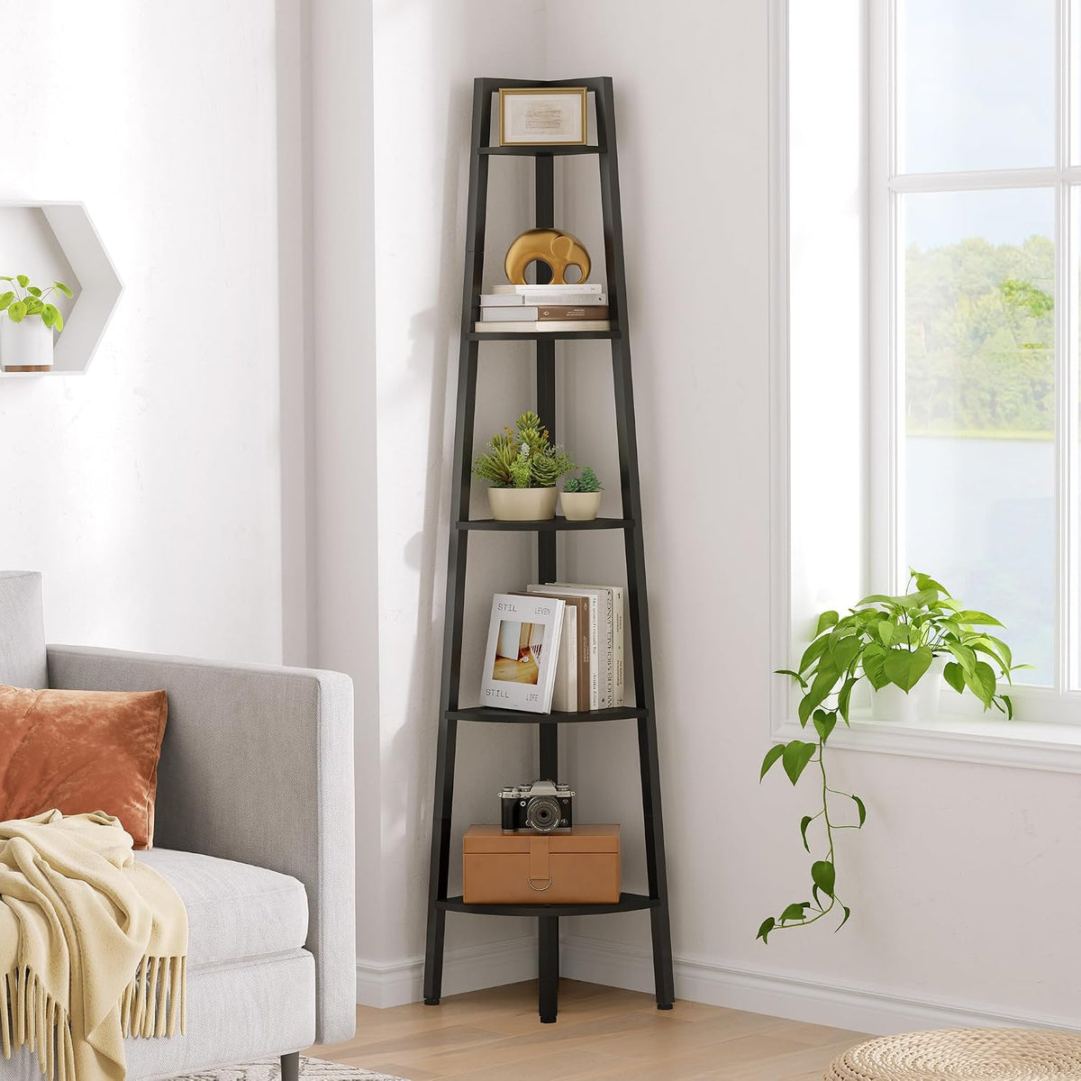 Angled view of the black corner shelf showing stacked books, small planters and a camera on lower tiers