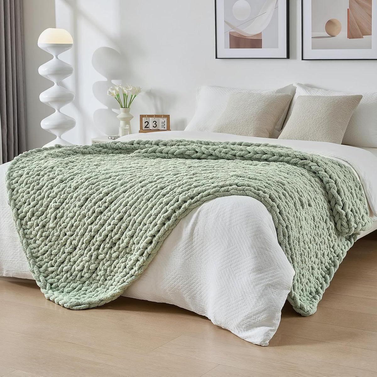 Soft mint-green chunky knit throw casually draped across a white bed in a styled room
