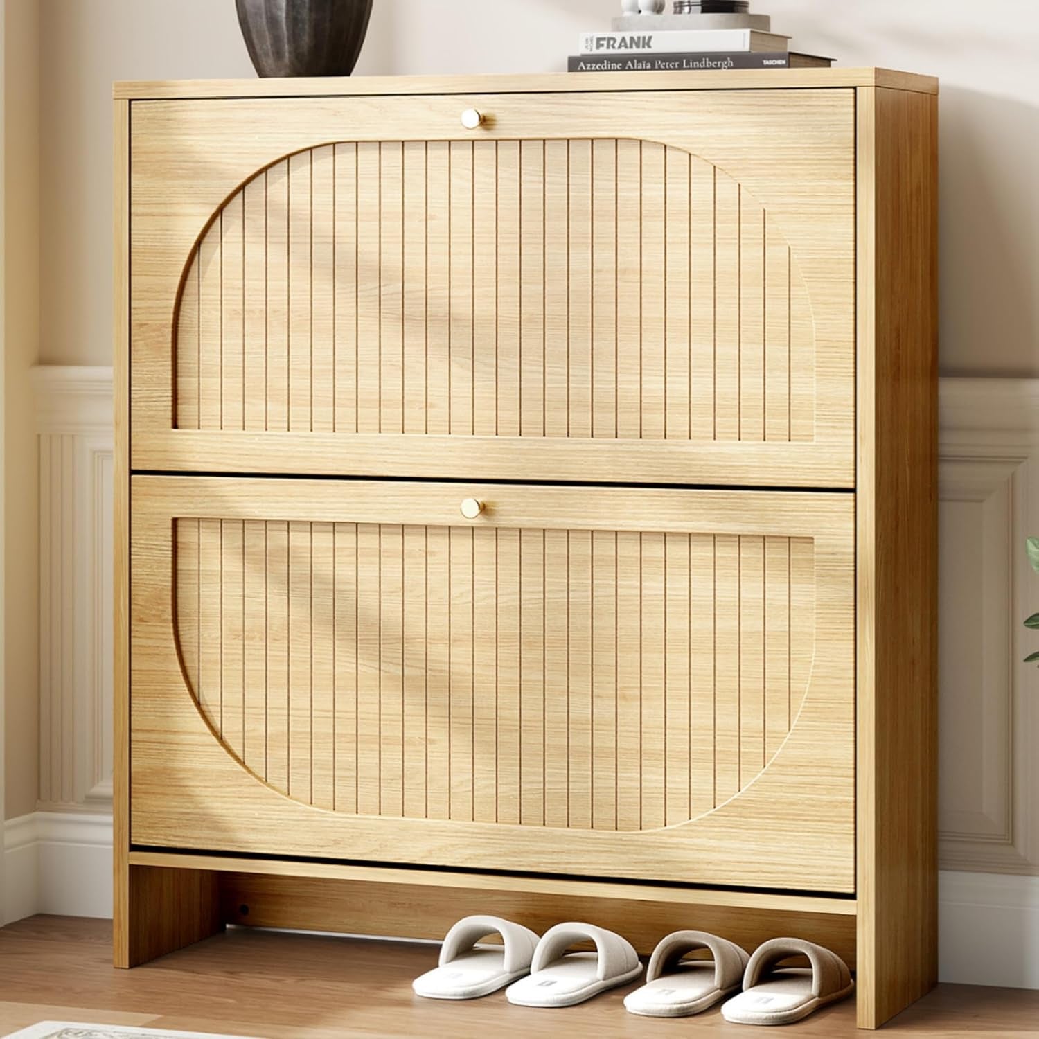 Head-on view of a narrow pale wood cabinet with large arched, vertical-slatted drawer fronts and a single round gold knob.