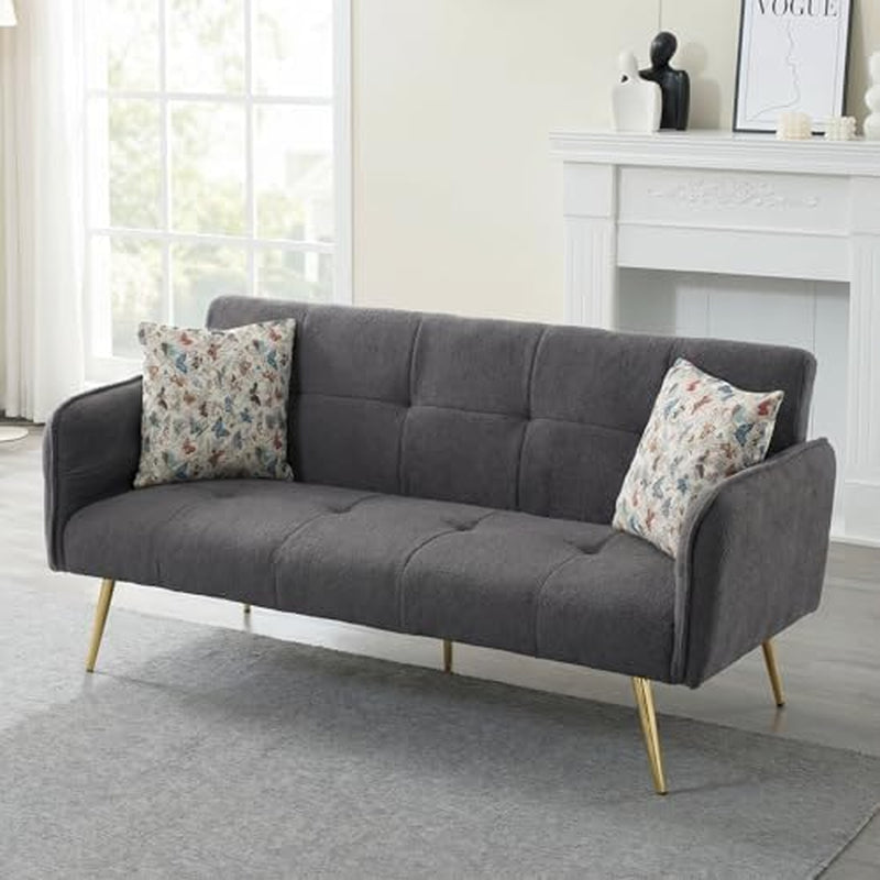 Three-quarter view of a dark gray velvet sofa with tufted seat and two butterfly-patterned throw pillows.