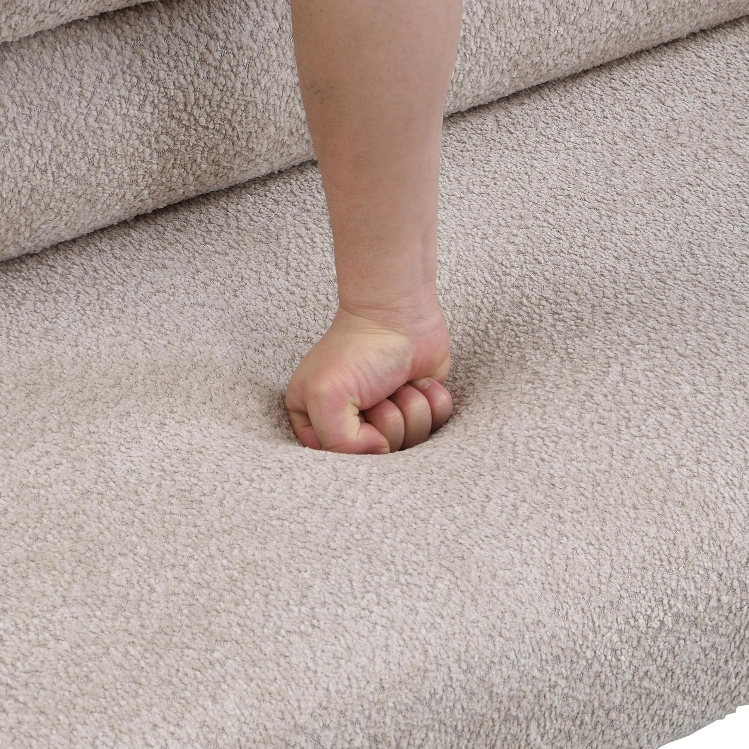 Close-up of a fist pressing into textured boucle upholstery, showing fabric give.