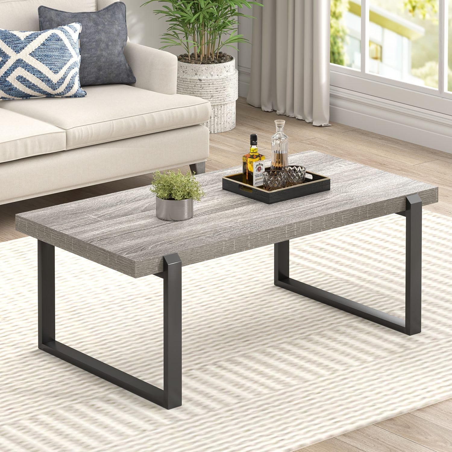 Light gray wood-grain tabletop with black metal legs shown on a pale patterned rug, tray and decanter on surface.