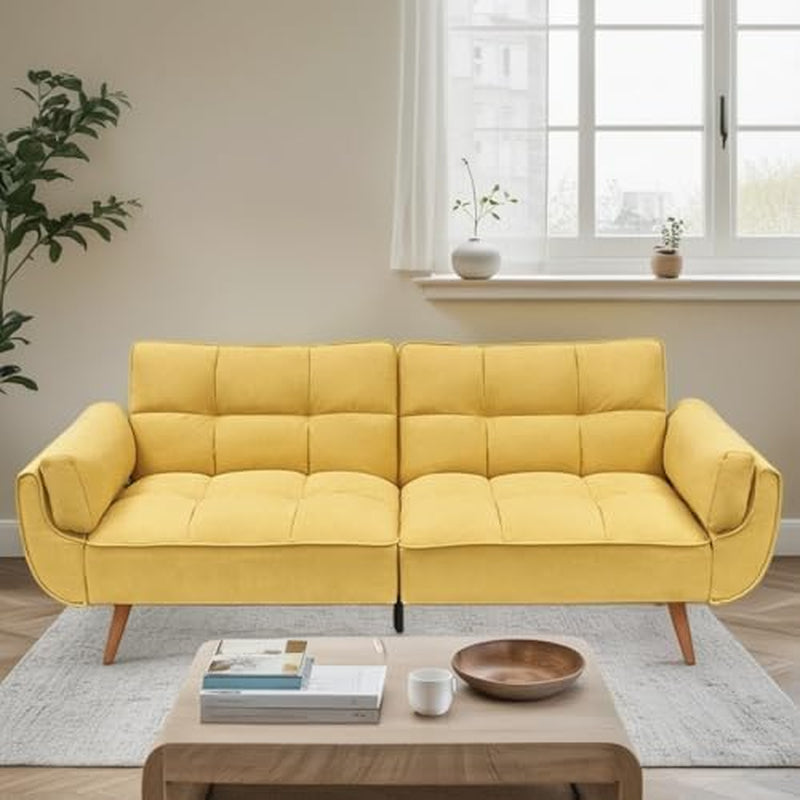 Bright yellow velvet futon sofa styled in a sunlit living room with a low coffee table.