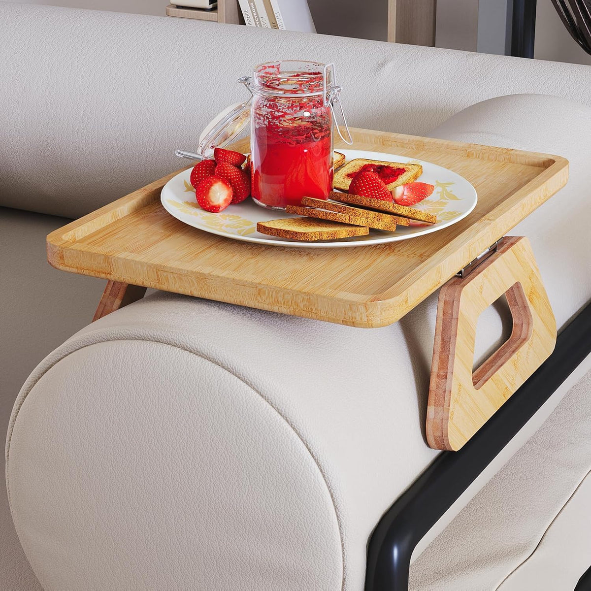 Bamboo arm tray holding a plate, jar, and snacks, showing the tray's rim and hinge side on a light sofa arm