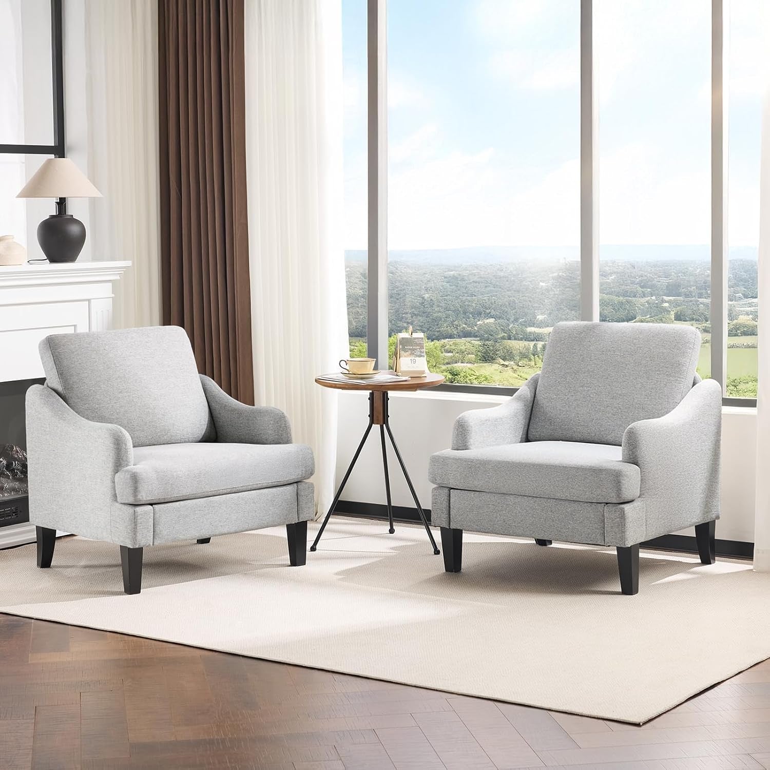Two light gray upholstered armchairs facing forward with a small round table between them.