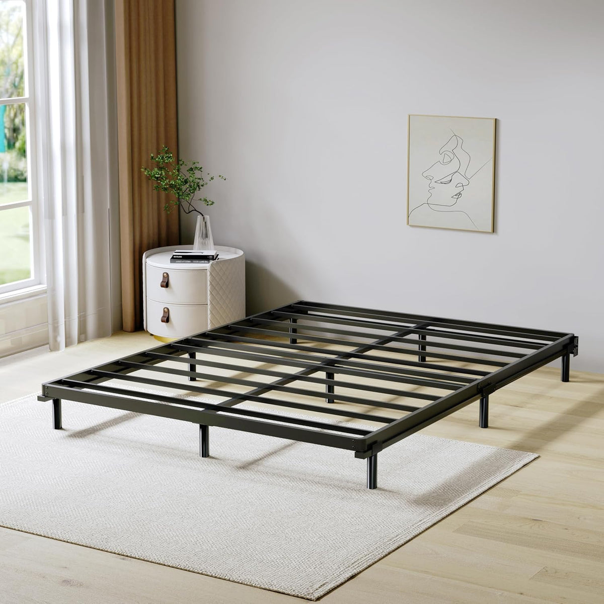 Front corner view of the black metal slatted box spring frame with center support legs in a bedroom