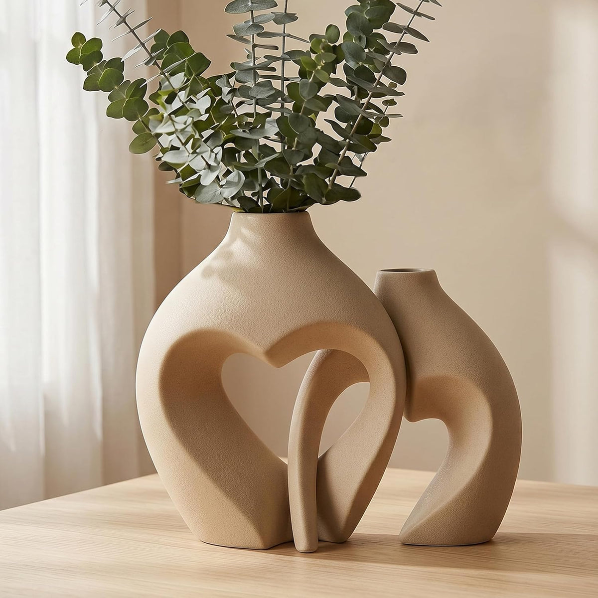 Close crop of the sand-glazed vases showing textured matte surface and eucalyptus stems