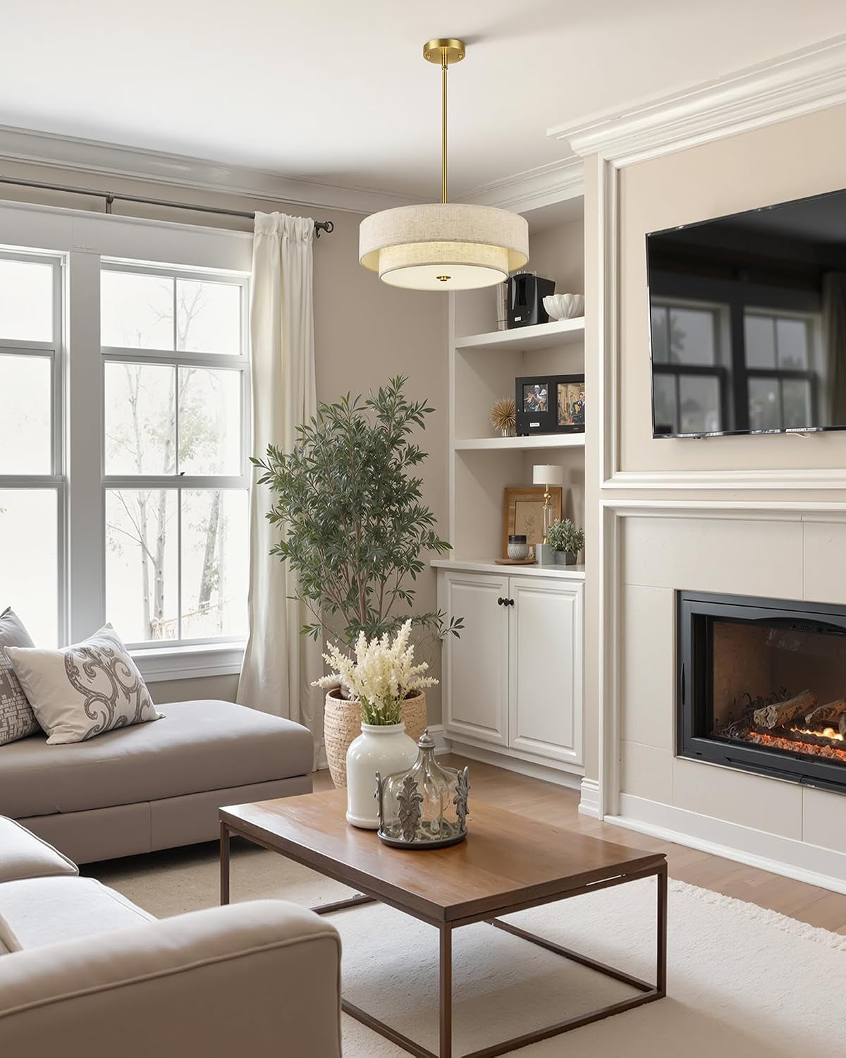 Beige two-tier drum chandelier hanging in a living room setting with a gold metal canopy and rod