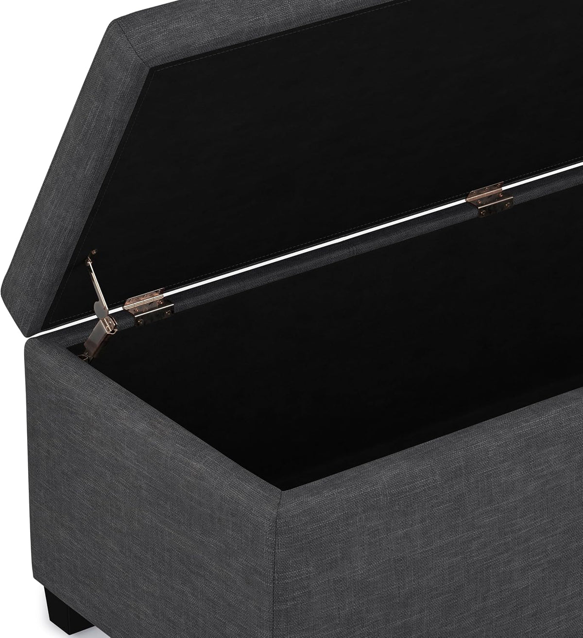 Open ottoman lid showing deep black fabric-lined storage compartment and metal hinge hardware.