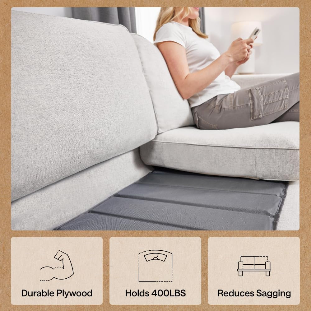 Grey sofa support board visible under a seat cushion in a light gray sofa with a person seated