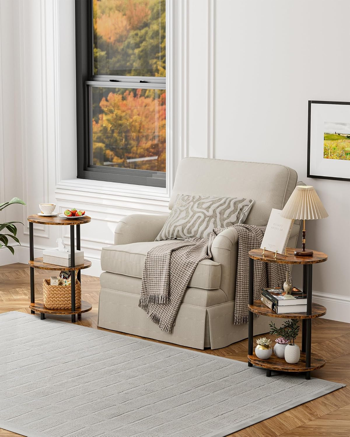 Three-tier round wood end table next to a beige armchair, holding books, lamp, and plants