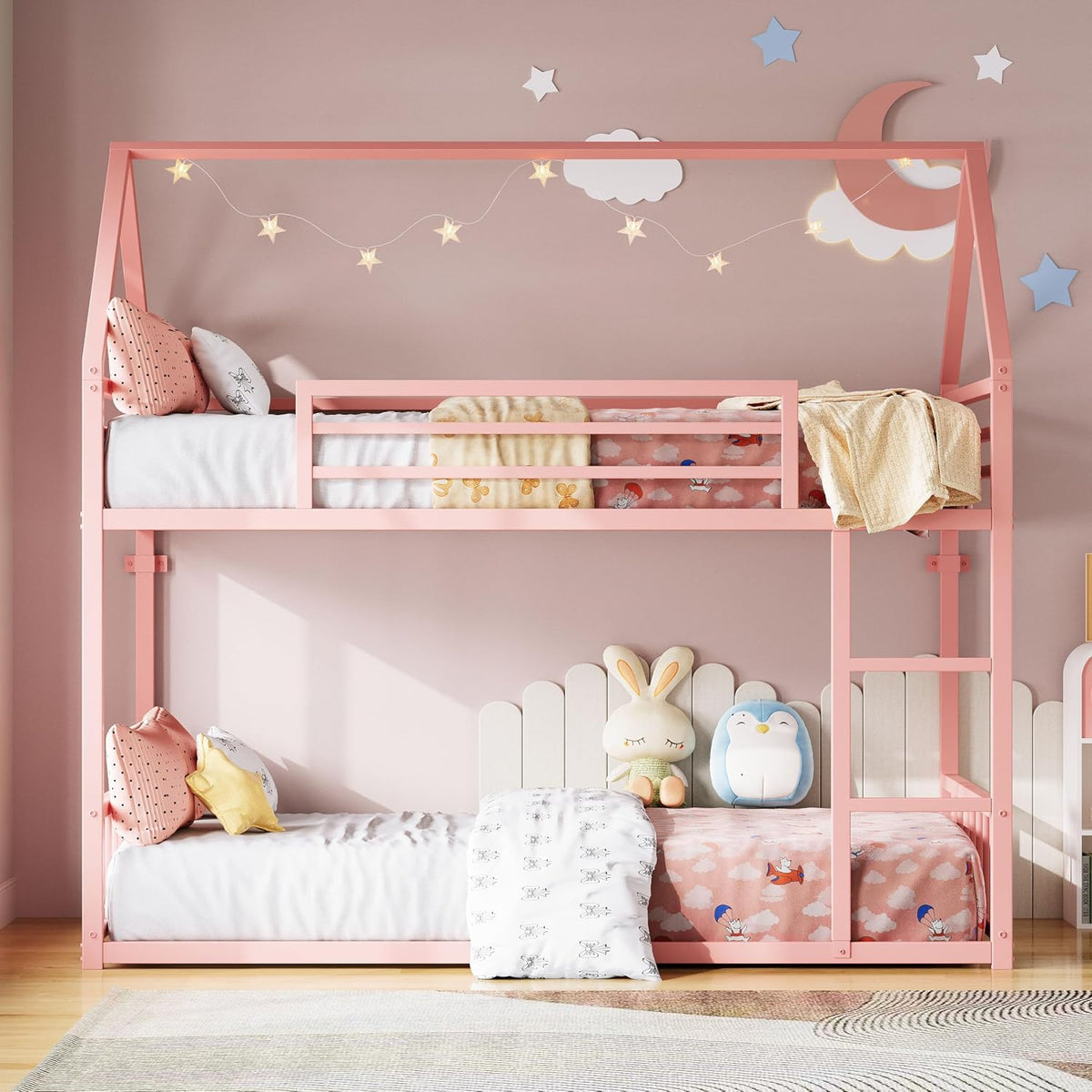 Pink twin-over-twin house-style bunk bed staged in a kids' room with toys and star lights