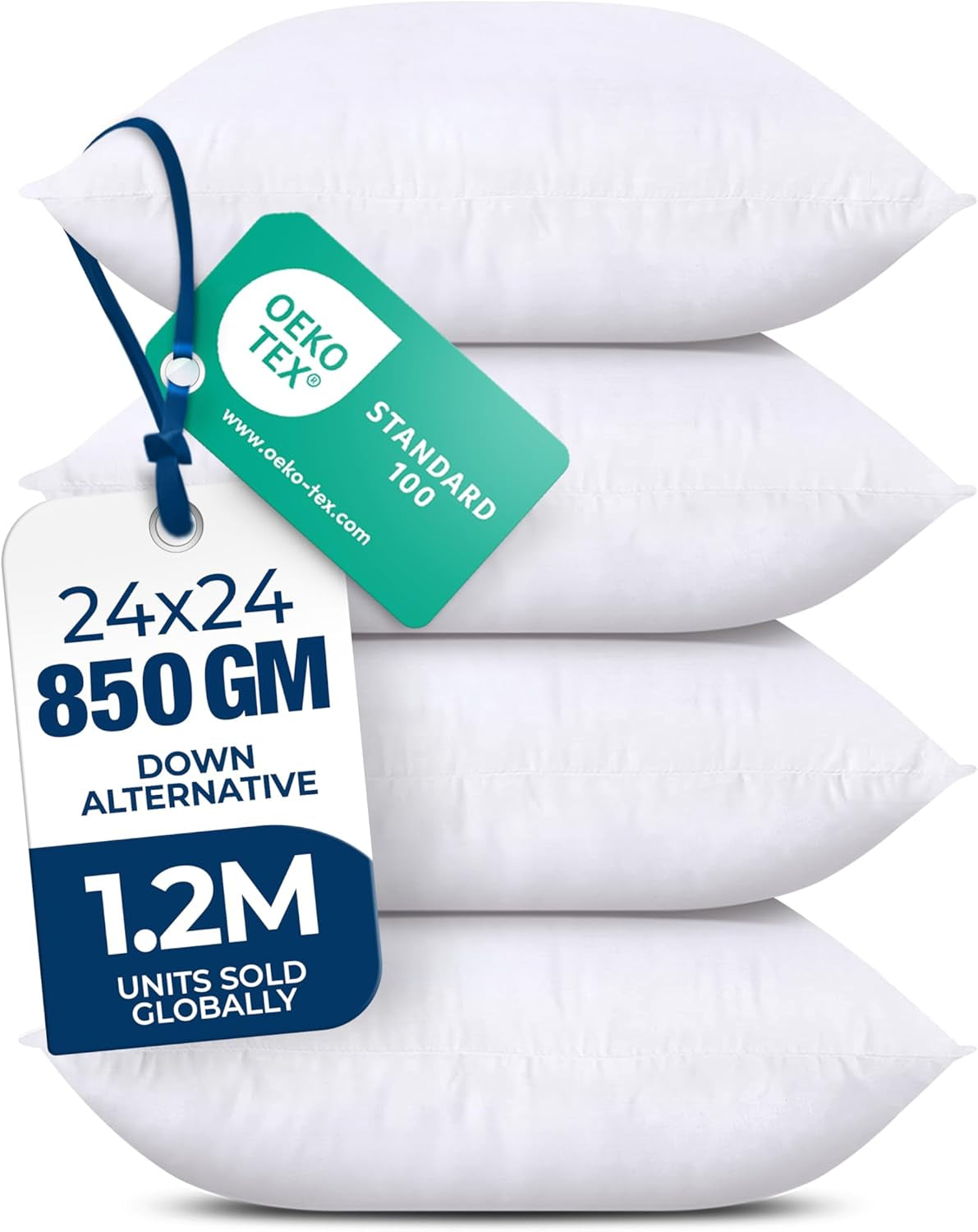 Four white throw pillows stacked, photographed from slight left angle with a large white and green hanging tag