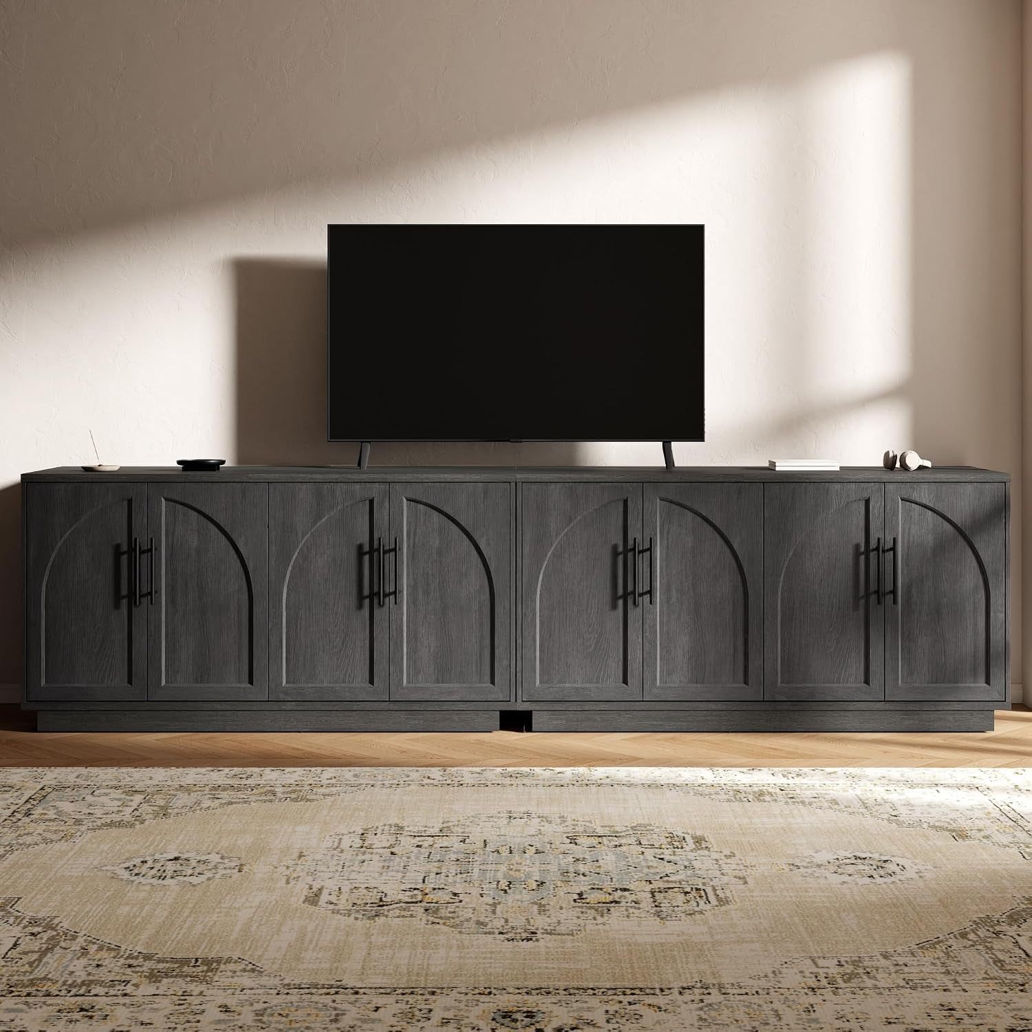 Dark gray buffet with four arched recessed panels and vertical black handles under a TV.