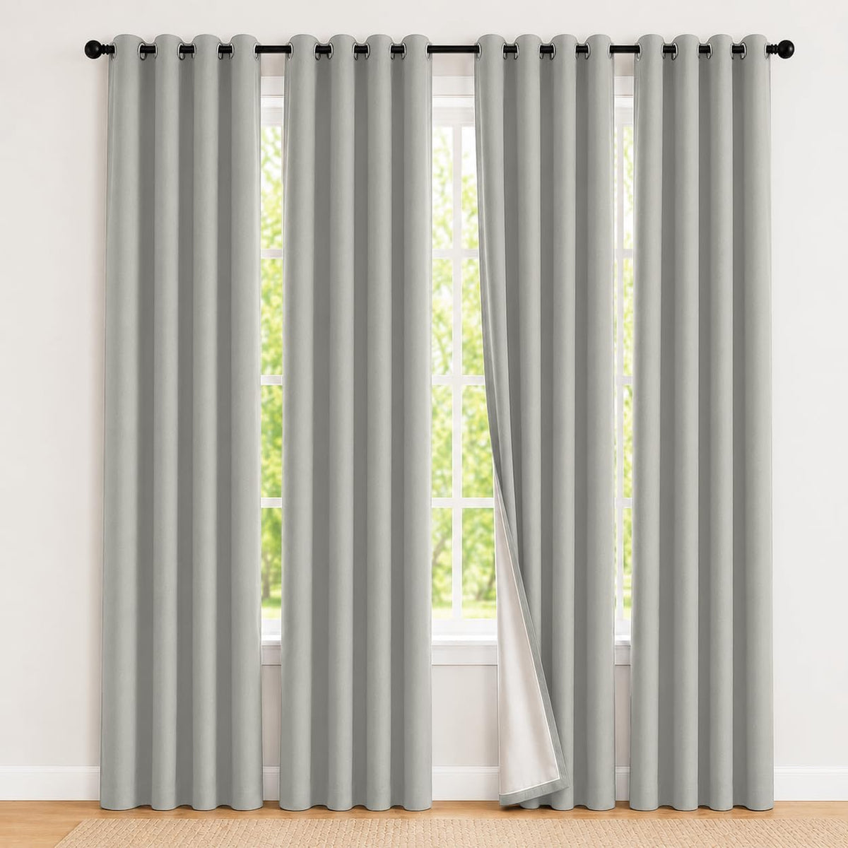 Full-length light gray grommet curtains hung on a black rod covering a large window.