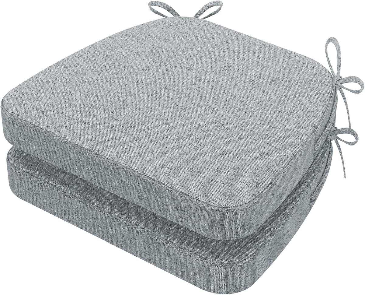 Angled shot of two light gray cushions stacked, showing rounded front edge and tied loops at the top corner.