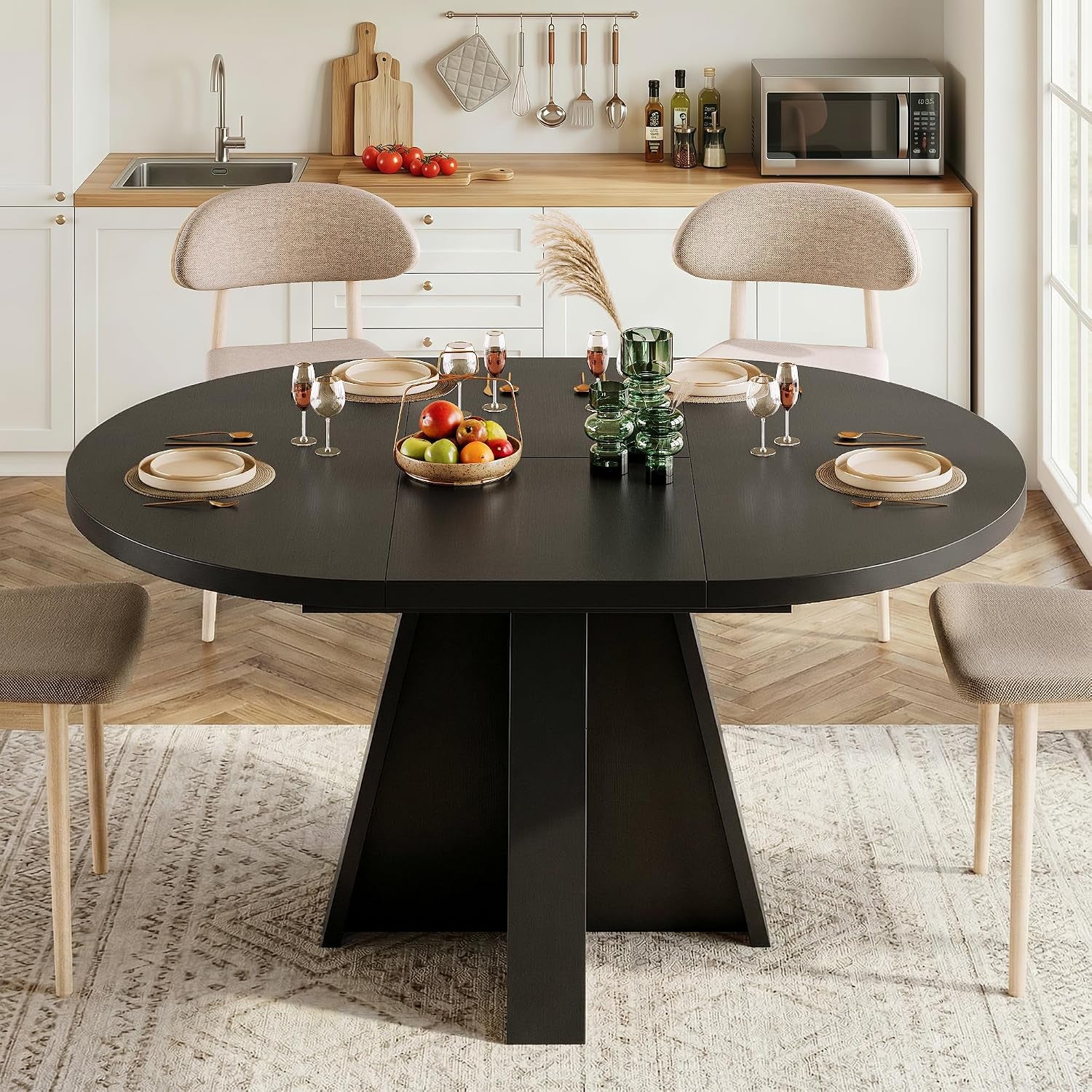 Front view of black round dining table with three-panel top and four chairs in a bright kitchen