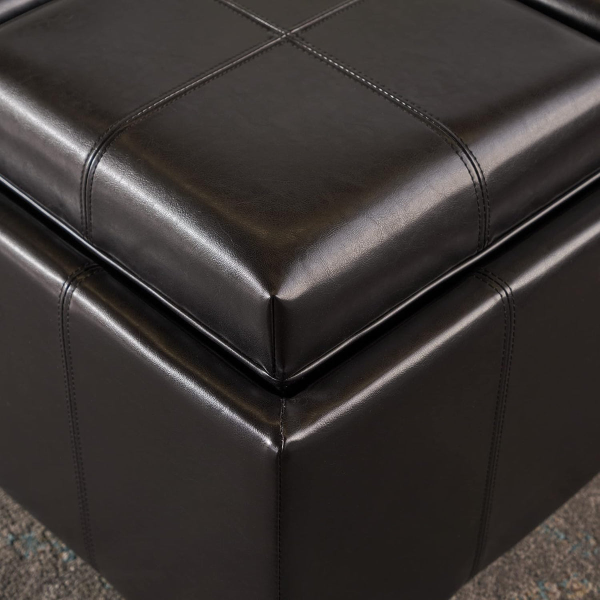 Close-up of a corner showing brown bonded leather upholstery and stitched seam detail on the flip-top cushion